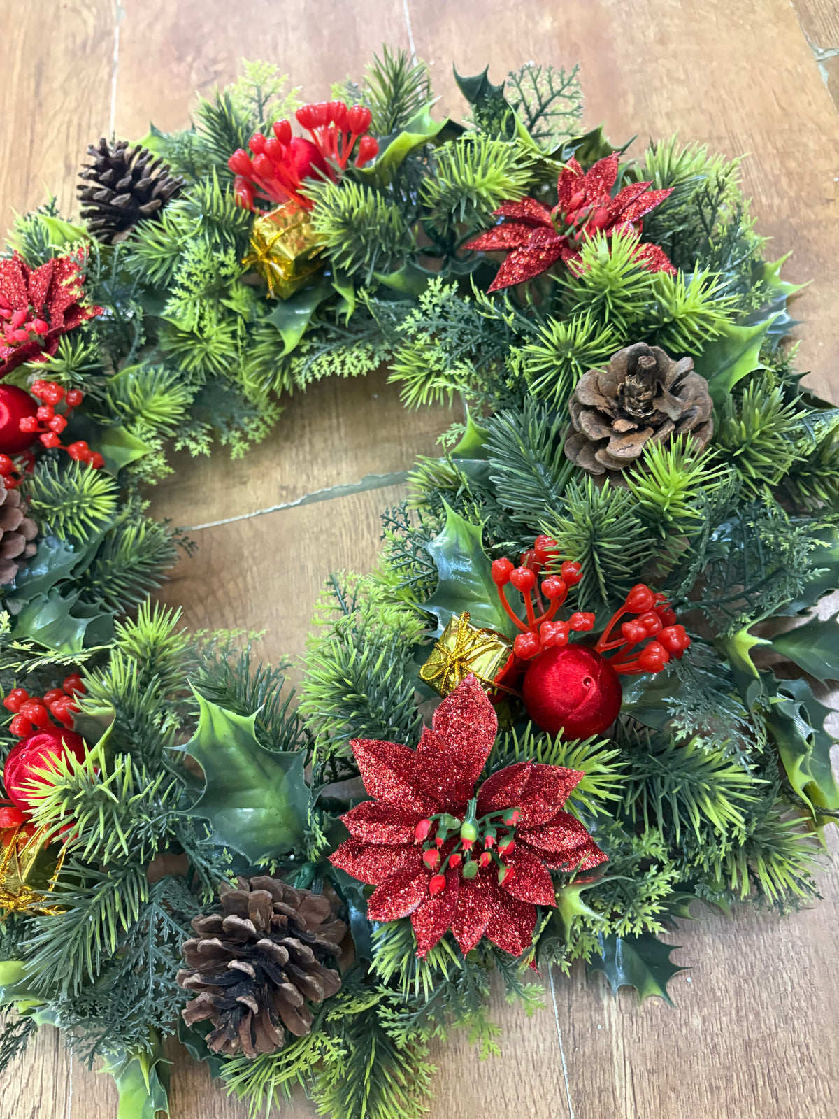 18” wreath with red poinsettias, cones, gifts and glitter balls
