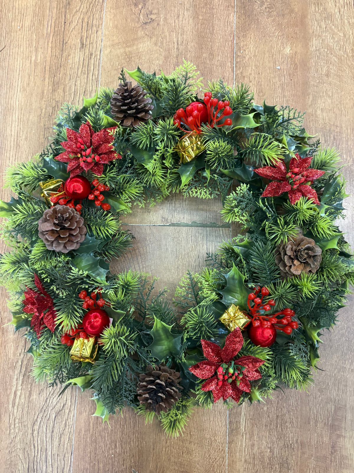 18” wreath with red poinsettias, cones, gifts and glitter balls