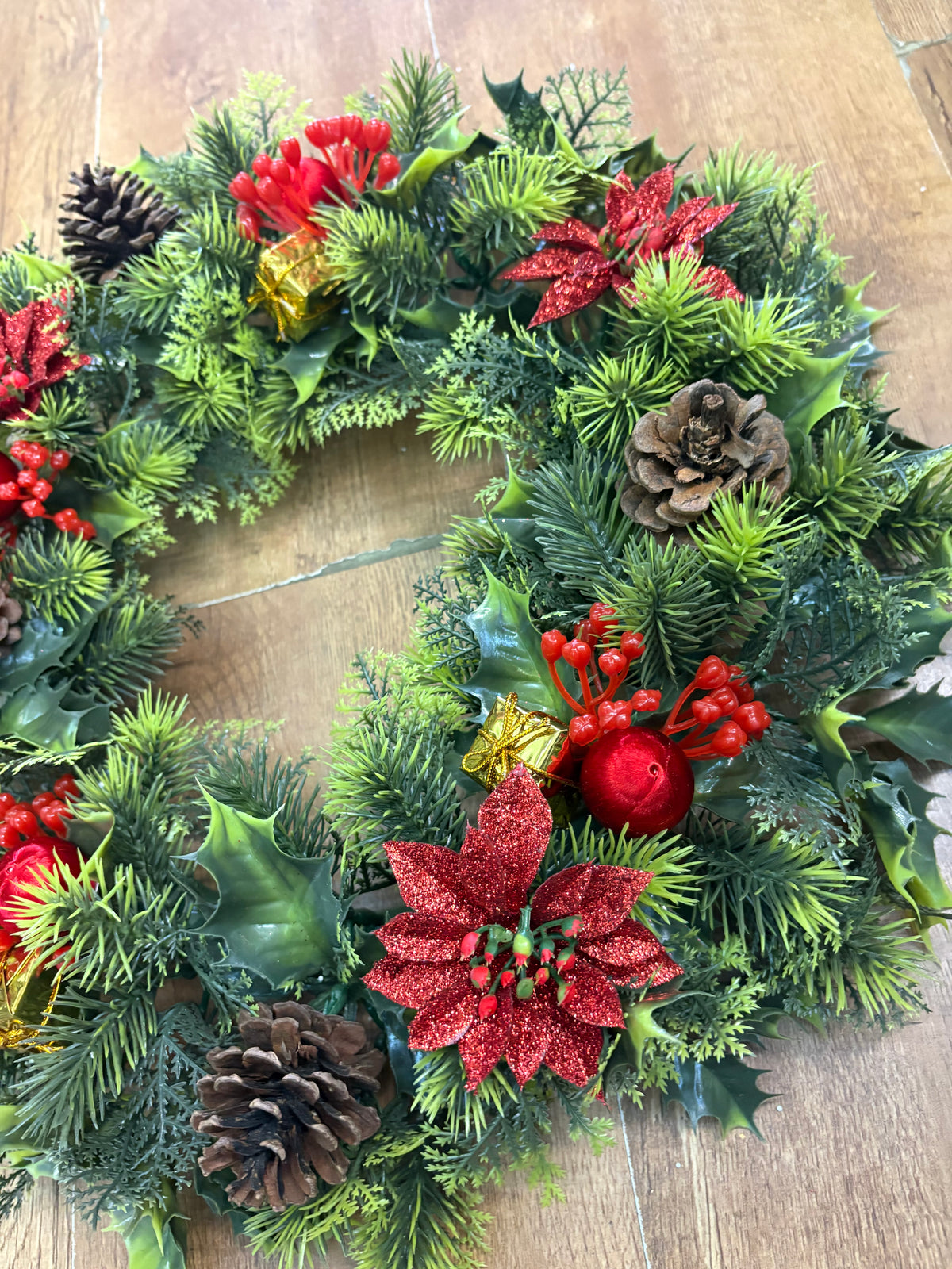 18” wreath with red poinsettias, cones, gifts and glitter balls