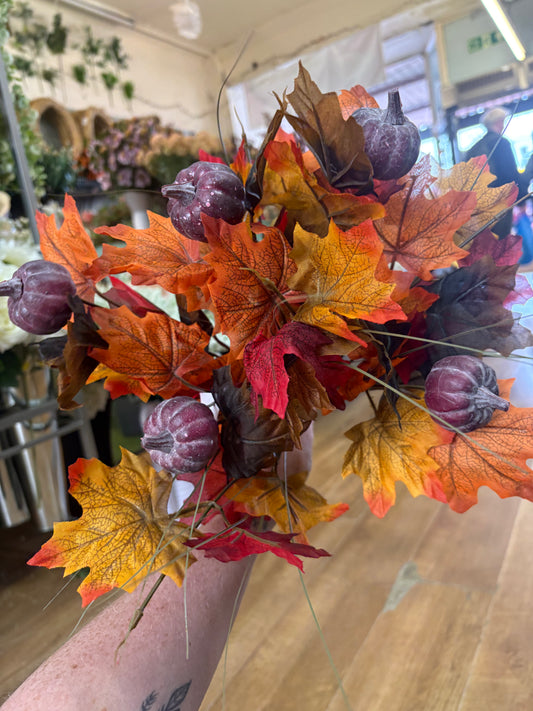 Large autumn leaves and dark pumpkins bunch